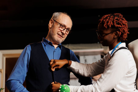 Elderly gentleman happy with perfect fit of bespoke suit vest made by professional meticulous suitmaker. Client satisfied with precise craftmanship done by expert couturierの写真素材