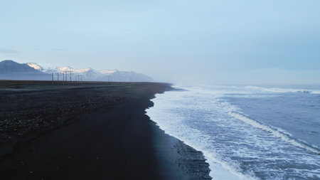 Drone shot of atlantic ocean with black sand beach in icelandic scenery, fantastic nordic landscape with coastline in iceland. Arctic country with majestic nature and scenic route. Slow motion.の写真素材