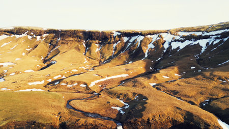 Aerial view of foss a sidu waterfall creating fantastic frozen landscape, icelandic scenery. Beautiful scandinavian cascade running down off of hills, scenic route. Slow motion.の写真素材