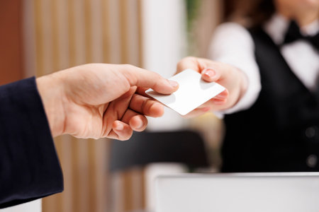 Staff handing room access card to client, white collar worker travelling on business trip. Man in suit approaching front desk to register on online booking, receive key. Close up.の写真素材