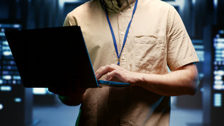 IT developer using laptop to audit energy consumption across server farm components and distributors. Programmer making sure data center hardware temperature sensors are performing flawlessly, close upの素材