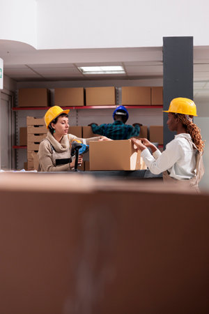 Storehouse workers using box sealing tape for packing parcel together. Ecommerce storehouse...