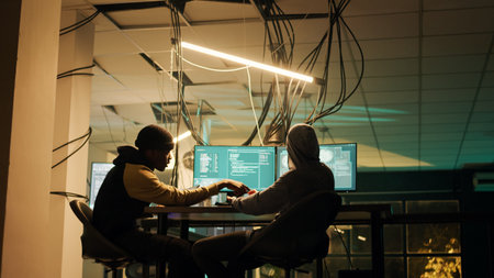 Diverse people using trojan virus to exploit server vulnerability, hacking computer system late at night. Cyber criminals working with encryption to hack software and break security firewall.の写真素材