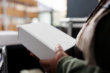 Storage room worker holding white cardboard boxes, checking products before shipping packages in warehouse. Stockroom supervisor working at customers orders during merchandise inventoryの写真素材