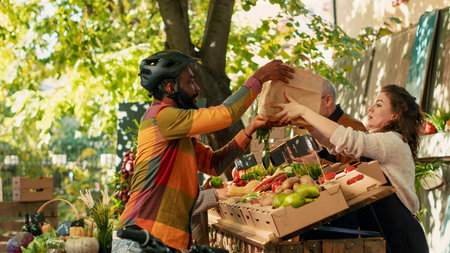 Female vendor giving frutis and veggies order to deliveryman, picking up food to deliver to...