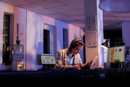 Joyful corporate employee analyzing financial growth report while listening music, working overtime...
