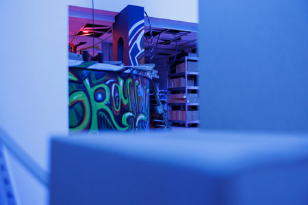 Deserted place illuminated by purple bright lights, graffiti glowing in the dark looking grungy. Abandoned building with spray paint and fluorescent neon light, empty ruined space.の写真素材