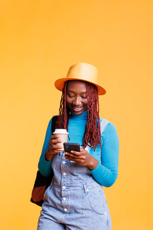 Female tourist texting messages, drinking cup of coffee in studio and travelling to international...