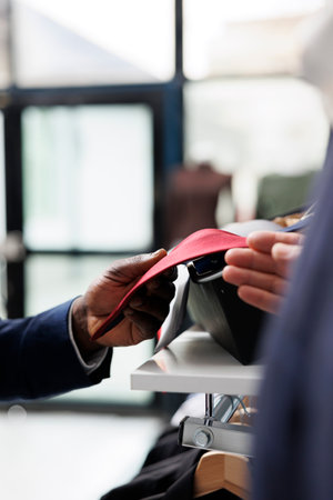 African american employee helping customer choosing tie, checking material before buying in clothing centre. Elderly client shopping for trendy clothes and merchandise in showroom. Close upの写真素材