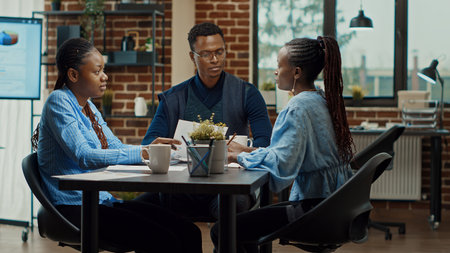 Employees reviewing annual data on files and screen, checking online reports statistics in coworking space. Business people thinking about development vision to plan new project. Tripod shot.の写真素材