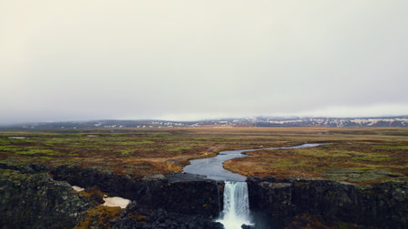 Majestic oxarafoss cascade panorama, aerial view of icelandic waterfall running down of mountain. Massive river stream flowing and falling off big rocky cliffs in iceland. Slow motion.の写真素材