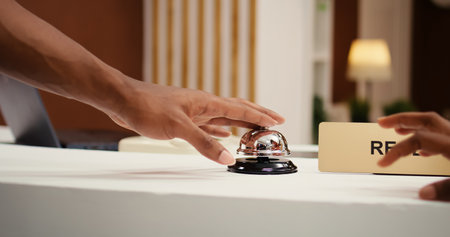 Close up shot of african american tourists ringing service bell at reception counter during booking...