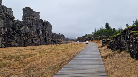 Rocky mountain range in arctic scenery, thingvellir national park with spectacular landscapes and massive cliffs in iceland. Rock formations creating hills in icelandic valley with walkway.の写真素材