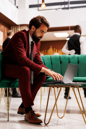 Entrepreneur reads papers in hotel lobby, waiting for check in registration before attending official conference. Businessman reviewing presentation notes for corporate meeting abroad.の写真素材