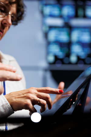Trained technicians updating data center hardware, writing intricate binary code scripts on tablet,...