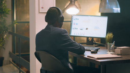 Employee enjoying music, bopping his head to rythm while solving company project tasks during...