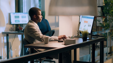 African american expert accountant sitting at desk during nightshift, working on business revenue...