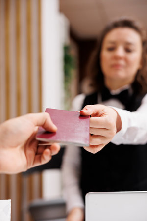 Guest gives passport for identification at check in, providing necessary documents at front desk....