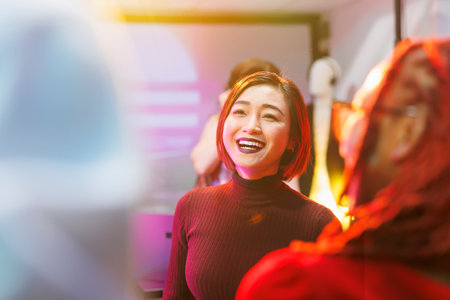 Smiling happy asian woman partying in nightclub with spotlights and having fun. Cheerful girl dancing and clubbing at discotheque, enjoying nightlife entertainment in clubの写真素材