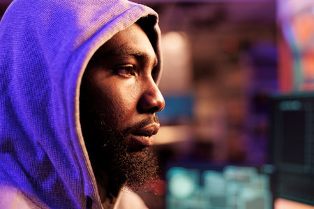 African american hacker in hood breaking into computer network system and hacking server. Young man...