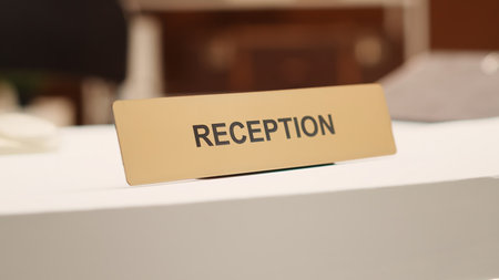 Close up of hotel lobby check in reception plaque sign and folders of tourist accommodation...