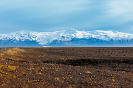 Gorgeous highland view in icelandic region, with snow covered mountains and frozen pastures in distance. Roadside picturesque roadway with northern landscape of hills and fields in Iceland.の写真素材
