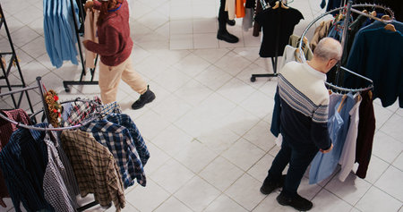 Top down view of clients walking around bustling shopping mall fashion shop aisles, looking to purchase clothes as presents for family and friends during Christmas promotional sales eventの写真素材