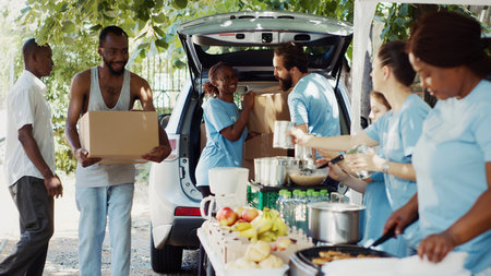 Group of multiethnic volunteers deliver food boxes and canned items to the needy and underprivileged. Voluntary individuals offer humanitarian relief to the poor and homeless people. Tripod shot.の写真素材