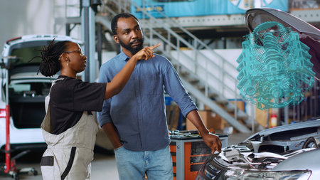 Mechanic in car service using holographic augmented reality to show woman defective components...