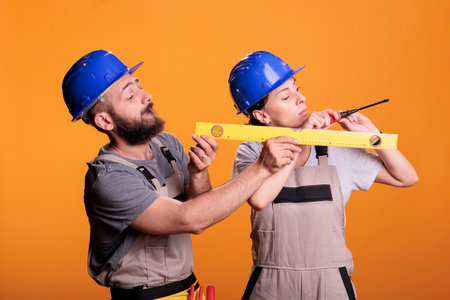 Contractors holding screwdriver and water level tool in studio shot, using ruler or leveler to work on renovation. Team of building experts being confident with renovating tools.の写真素材