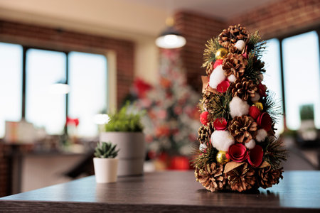 Decorated artificial christmas tree with ornaments and houseplant in festive office workplace...