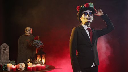 Scary holy entity in halloween costume with skull make up celebrating holy mexican tradition, looking like lady of death. Santa muerte ritual celebration with black and white body art in studio.の写真素材