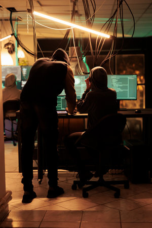 Team of spies using trojan virus to crack encryption and steal government information from database. Committing cyberattack and cybercrime with malware, access program late at night.の写真素材
