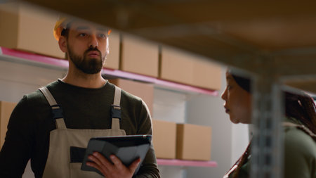 African american warehouse manager and trainee perform inventory check, keeping quality standards high. Organized experts in stockroom prepare to ship parcels, crosschecking delivery infoの写真素材