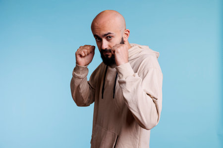 Young arab man standing in aggressive pose with clenched fists, ready to fight portrait. Angry...