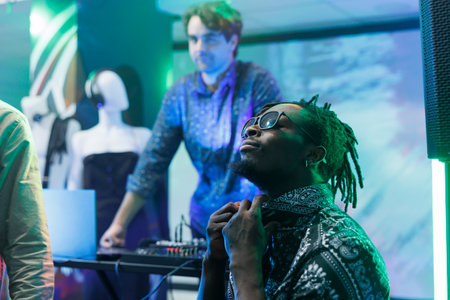 Cool african american man in sunglasses relaxing and sitting in nightclub. Young modern clubber resting while clubbing and enjoying nightlife entertainment at disco eventの写真素材