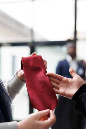 Elderly customer holding red tie analyzing material in clothing centre, shopping for formal clothes...