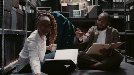 African american agents examining physical evidence to uncover new clues on case files, conducting criminal investigation. Private inspectors analyzing surveillance photos in police archive.の写真素材