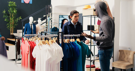 Robber trying to stole stylish clothes from shopping mall, being caught by asian security guard. African american couple arguing with bodygurad, trying to escape crime accusation in modern boutiqueの写真素材
