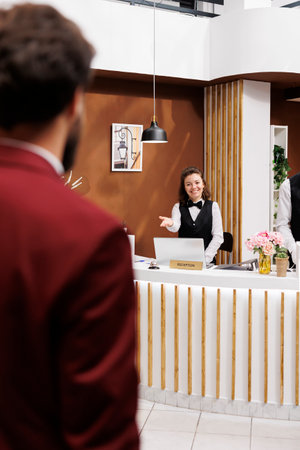 Employee welcoming businessman in lobby, providing luxury services for guest travelling on work trip. Guest arriving at resort with baggage, receiving friendly assistance from hotel staff.の写真素材