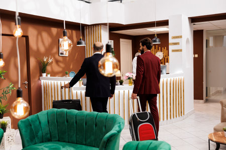 Business partners travel for work purposes, preparing to check in at luxury hotel. Men in elegant tailored suits travelling for company international conference, white collar workers on trip.の写真素材