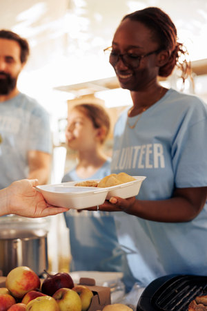 Detailed picture shows volunteers providing free food to the hungry, homeless, and refugees. Close...