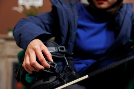 Close up shot of tourist securing snowboarding gear in hotel foyer, prepared for winter vacation at ski resort. Detailed view of person inspecting a snowboard, getting ready for snowy adventure.の写真素材