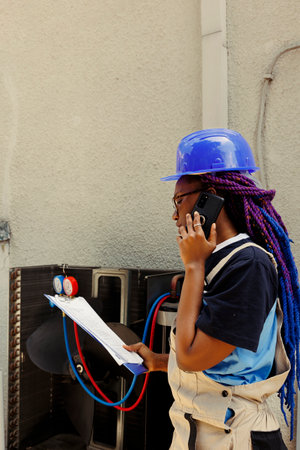 African american specialist asking manager for advice over the phone about air conditioner needing...
