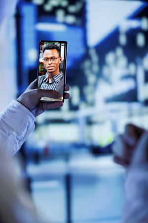 Woman in videocall with husband while walking around city streets at night, close up. Citizen using smartphone to show spouse surroundings in dimly illuminated urban center in blurry backgroundの写真素材