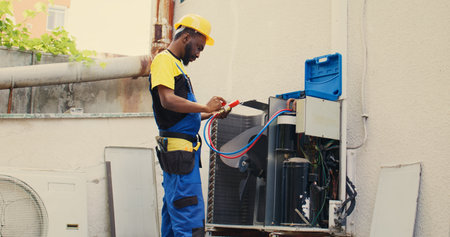 Skillful serviceman calibrating set of barometer meters during comissioned condenser analysis. Precise professional looking for potential high pressure in hvac system cooling system, close upの写真素材