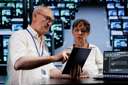 Data storage company executives running analysis on mainframes used for managing databases, hosting websites and storing files. Seasoned specialists auditing high tech server room partsの写真素材