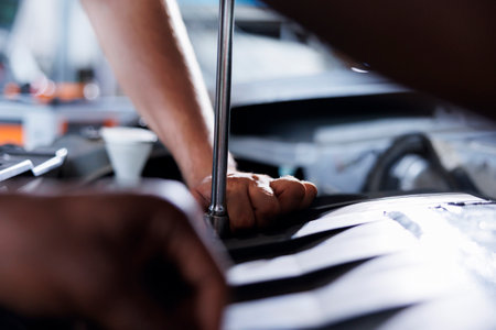 Colleagues in car service use torque wrench to tighten bolts after replacing fuel tank. Precise auto repair shop employees use professional tools to fix customer automobile, close upの写真素材