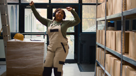 Chilled warehouse employee listening music enjoying herself while checking labels on cardboard...