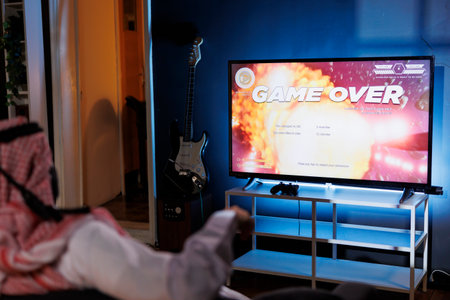 Islamic guy defeated in an online video game from the comfort of his home. Lit by the glow of the...